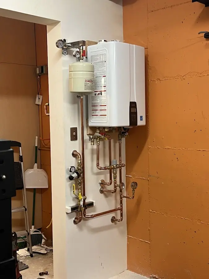 Plumbing technician inspecting water heater connections in Chelmsford